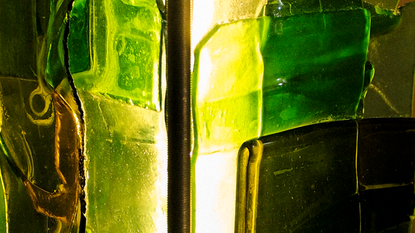 Abstract close-up of translucent green glass panels with bright yellow-green highlights and a vertical dark line through the center.